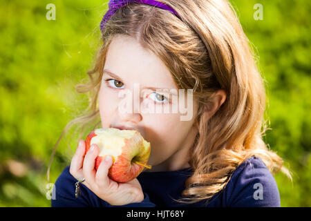 Capretto felice mangiare frutta dal cesto picnic seduto sull'erba verde Foto Stock