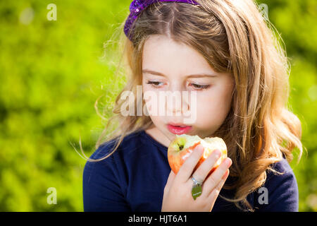 Capretto felice mangiare frutta dal cesto picnic seduto sull'erba verde Foto Stock