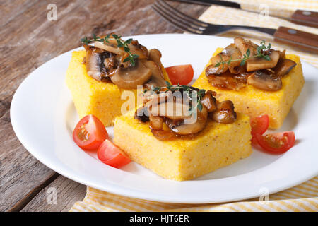 Polenta con funghi, pomodori e timo sul tavolo. primo piano orizzontale Foto Stock