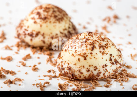 Due vaniglia pearl caramelle e cioccolato fondente grattugiato su sfondo bianco Foto Stock