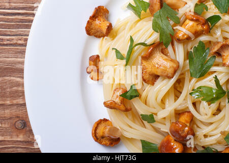 Pasta Spaghetti con funghi finferli su uno sfondo di legno vista macro della parte superiore orizzontale Foto Stock