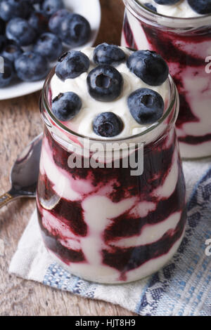 Yogurt con mirtilli in un vaso di vetro vicino la vista verticale da sopra Foto Stock