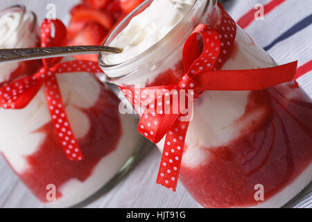 Yogurt alla fragola in un vasetto con un cucchiaio di close-up sul tavolo orizzontale Foto Stock