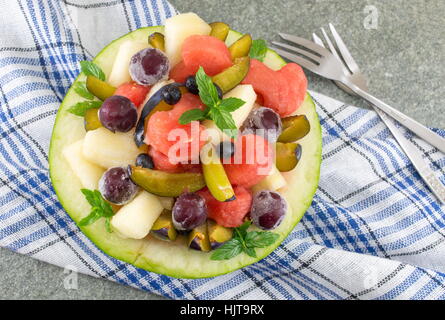 Macedonia di frutta fresca servita in un melone con heartshaped watermellon fette Foto Stock