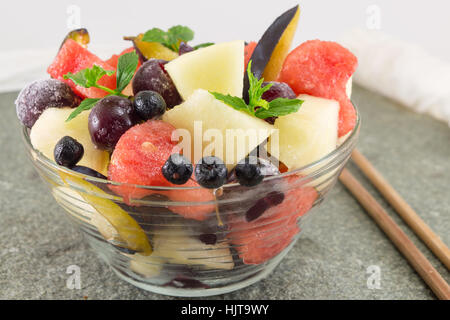 Macedonia di frutta fresca servita in una ciotola di vetro con heartshaped watermellon fette Foto Stock