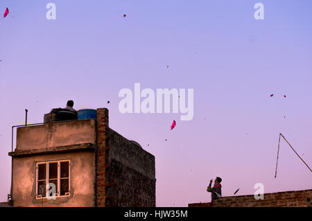 Jaipur, India - 14 GEN 2017: gente volare aquiloni da tetti di case incompiuto sul Makar Sankranti al tramonto Foto Stock