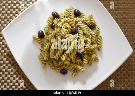 Fusilli conditi con il pesto, olive nere e capperi. Pasto pronto da mangiare Foto Stock