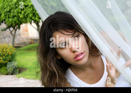 Bambina che si nasconde dietro la tenda Foto Stock