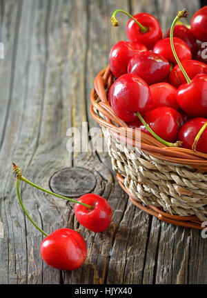 Rosso di ciliege dolci in un cesto su legno vecchio Foto Stock