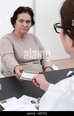 Medico di prescrivere il farmaco al senior paziente femmina-messa a fuoco selettiva Foto Stock