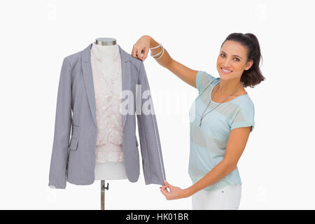 Designer di moda la misurazione blazer manicotto sul manichino e sorridente su sfondo bianco Foto Stock