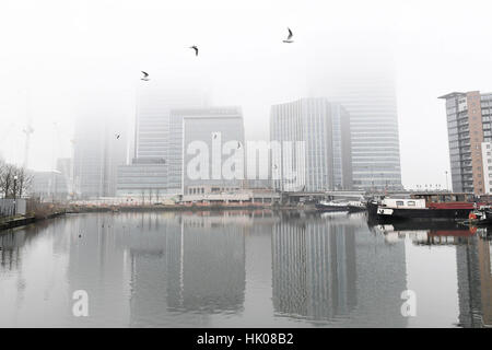 Nuvole di nebbia la vista del Canary Wharf nei Docklands di Londra. Foto Stock