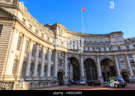 Admiralty Arch con il traffico di lasciare il Mall e Unione battenti bandiera, tardo autunno sun, London, England, Regno Unito Foto Stock