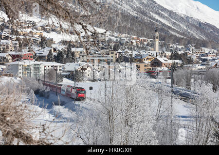 Il trenino rosso corre attraverso il paesaggio innevato intorno a Samedan Maloja, Canton Grigioni, Engadina, Svizzera Foto Stock