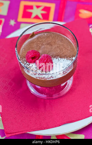 Decadente in casa mousse al cioccolato con lamponi freschi, su un tovagliolo rosso Foto Stock