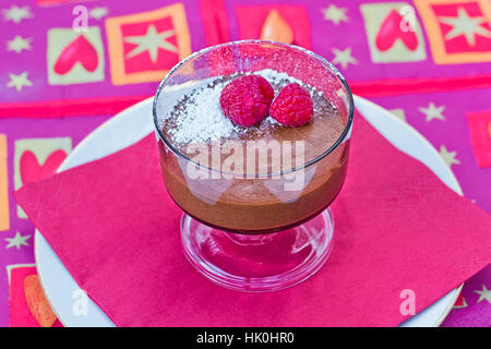 Decadente in casa mousse al cioccolato con lamponi freschi, su un tovagliolo rosso Foto Stock