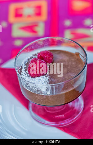 Decadente in casa mousse al cioccolato con lamponi freschi, su un tovagliolo rosso Foto Stock