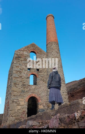 A woman looking at an old tin mine near Wheal Coates, Cornwall. Foto Stock