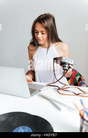 Foto di casual attraente bella donna al lavoro su un notebook seduta sulla poltrona di casa. Foto Stock