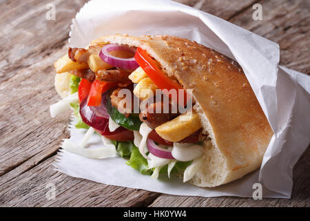 Döner Kebab con carne, frittelle di patate e verdure in pane pita close-up su un vecchio tavolo orizzontale Foto Stock