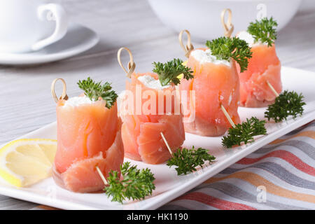 Finger food. Rotoli di salmone con crema di formaggio vicino sul tavolo orizzontale Foto Stock