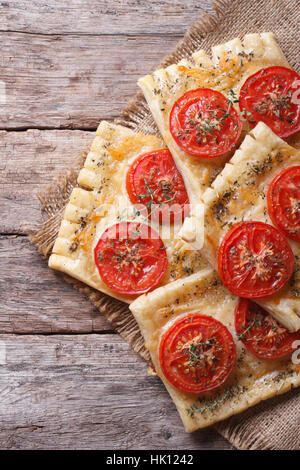 Torta di sfoglia con pomodoro e formaggio sulla tabella di close-up verticale. vista superiore Foto Stock