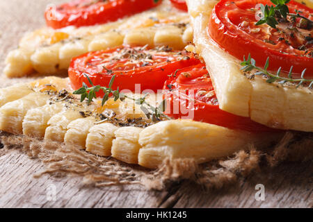 Torta di sfoglia con pomodoro, formaggio ed erbe sul tavolo macro. orizzontale Foto Stock