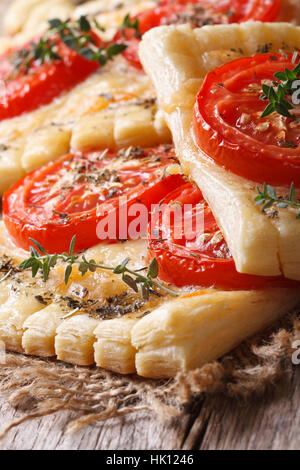 Puff di torte con pomodoro, formaggio ed erbe sul tavolo macro verticale. Foto Stock