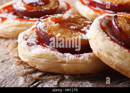 I dolci di pasta sfoglia con prugne macro su un vecchio tavolo orizzontale. Foto Stock