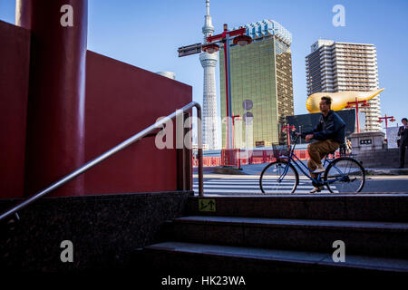 Townscape, ciclista. Nel cielo di sfondo albero, Asahi building e Azuma bridge, dall ingresso della metropolitana, il quartiere di Asakusa, Tokyo, Giappone. Foto Stock