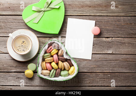 Amaretti colorati nel giorno di San Valentino a forma di cuore ad confezione regalo e una tazza di caffè sul tavolo di legno. Vista da sopra con lo spazio di copia Foto Stock