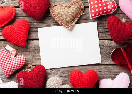Il giorno di San Valentino biglietto di auguri. Handmaded cuori, candy cuore e il foglio di carta sul tavolo di legno. Vista da sopra con lo spazio di copia Foto Stock