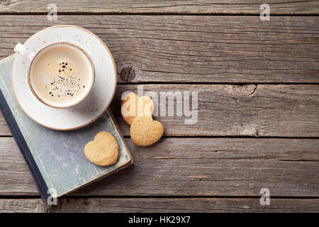 Tazza di caffè a forma di cuore i cookie sul tavolo di legno. Il giorno di San Valentino. Vista da sopra con lo spazio per i messaggi di saluto Foto Stock