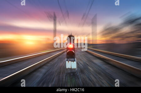 La stazione ferroviaria e il semaforo con motion blur effetto contro il cielo colorato con le nuvole al tramonto. Concetto di paesaggio industriale Foto Stock