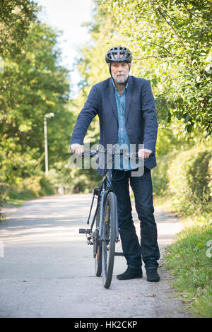 Il vecchio uomo con mountain bike e casco per bicicletta. Estate momento di uno stile di vita attivo con la persona anziana e vivere una vita sana. Foto Stock