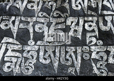 Mani di pietra scolpita con script tibetano e dipinto di bianco e nero Foto Stock