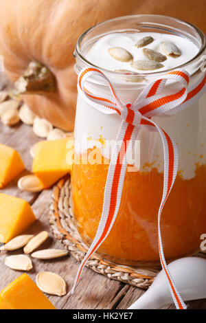 Dolce di zucca, lo yogurt e i semi in un vaso closeup verticale. Foto Stock