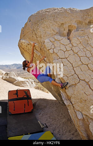 Donna di arrampicata a sbalzo un masso di granito vicino al Vescovo California Foto Stock