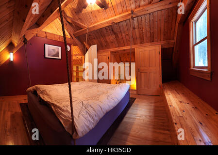 Attico mansarda camera da letto con un letto sospeso in un canadese timberframe country house, interno con un sacco di legno, Muskoka, Ontario, Canada Foto Stock