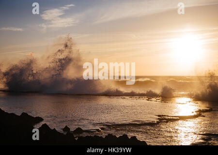 Grandi onde di colpire le rocce come il golden sun imposta sulla costa di hay el fath, Rabat. Marocco Foto Stock