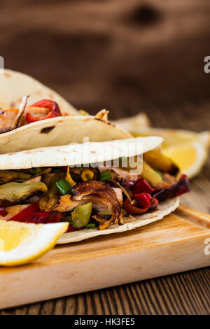 Le fajitas di pollo alla griglia con le cipolle e i peperoni e servire con tortilla di farina su rurale tavola di legno Foto Stock