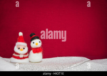 Santa Claus, pupazzo bambola di lana su neve impostato con panno rosso sfondo, felice anno nuovo e concetto di Natale sfondo con spazio di copia Foto Stock