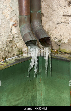 Acqua congelata forme ghiaccioli al fine di tubi di pioggia. Foto Stock