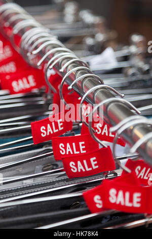 Le etichette in rosso con la parola vendita su grucce al di fuori del negozio di moda Foto Stock