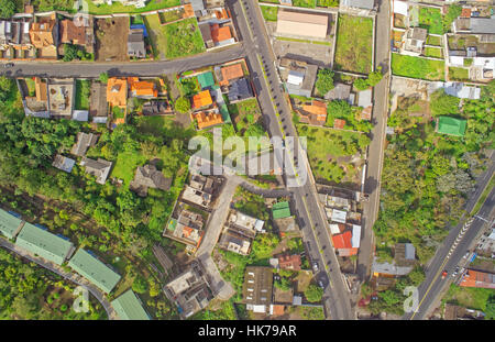 Una fotografia aerea dall'alto cattura un'area residenziale con un mix di case, alcune in costruzione, circondate da una lussureggiante vegetazione verde. La scena include strade intersecanti con visibile Foto Stock