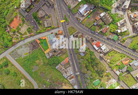 Una fotografia aerea cattura un incrocio stradale in un'area urbana ad uso misto. La strada principale passa verticalmente attraverso il centro, contrassegnata da linee di divisione gialle e linee di demarcazione bianche Foto Stock