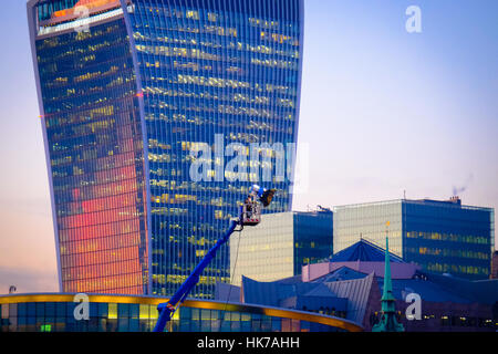 Un tramonto è riflessa fuori dalle finestre di stile futuristico edificio ufficio mentre una attrezzatura di illuminazione brilla sul set di un film. Foto Stock