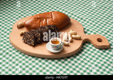 Salame di cioccolato con biscotti e nocciole sul tagliere Foto Stock