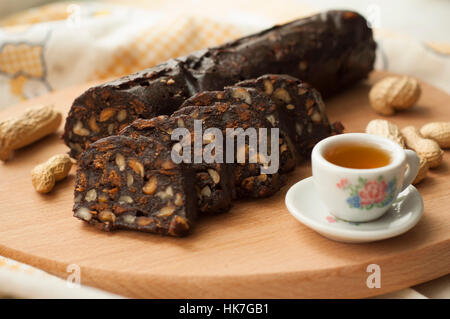 Salame di cioccolato con biscotti e nocciole sul tagliere Foto Stock