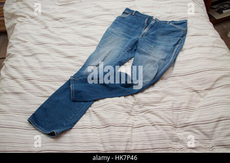 Indossare jeans blu su un letto quilt Foto Stock